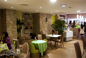 Intérieur coté droite avec plusieur petite tables et comtoire dans le fond (vue du fond du resto)